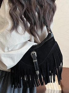 Sac à bandoulière en daim noir vintage avec franges et boucle western porté par mannequin