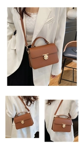 Detail of a brown lychee pattern leather handbag with gold oval clasp and adjustable strap