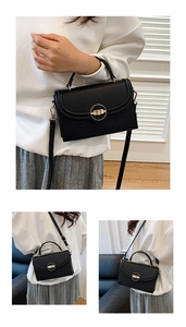 Detail of black pebbled leather crossbody bag featuring a golden circular twist lock closure