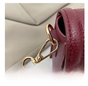 Detail of burgundy lychee leather handbag showing gold metal hook and precise stitching