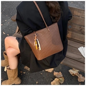 Detail of a large woven tote bag in dark brown with decorative colored wooden beads