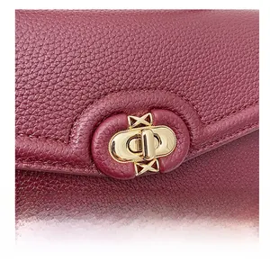 Detail of golden oval twist lock on dark red pebble grain leather crossbody bag