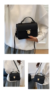 Detail of black lychee grain handbag featuring golden ring twist lock and shoulder strap