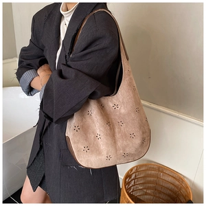 Detail of laser-cut floral patterns on brown suede hobo bag with leather trim