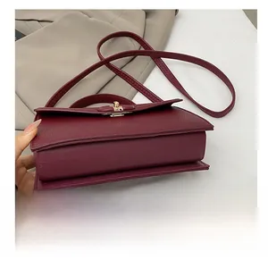 Macro detail of wine red lychee grain leather handbag with fine stitching and metal buckle