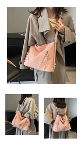 Detail view of pink suede tote bag with double zippers and star charm in outdoor setting