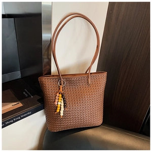 Close-up of deep brown woven tote bag featuring intricate texture and beaded charm detail