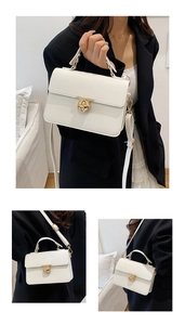Detail of white litchi pattern leather handbag featuring a golden round twist lock buckle