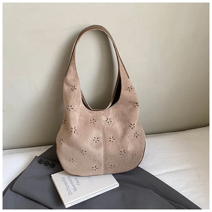 Macro detail of khaki suede hobo bag featuring laser-cut floral hollow patterns
