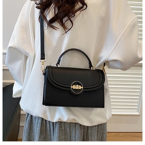 Detail of black crossbody square bag with lychee texture and golden metal clasp