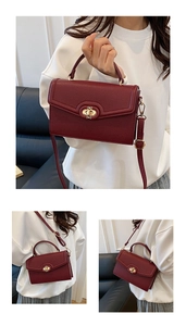 Detail of burgundy lychee grain leather handbag with gold bow rotating lock and handle