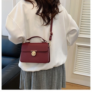 Chic burgundy square leather bag with gold buckle shown on shoulder in stylish interior