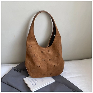 Close-up of brown suede hobo bag with laser-cut floral patterns and smooth leather handle