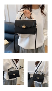 Detail of black lychee grain leather handbag featuring a golden metal twist lock closure