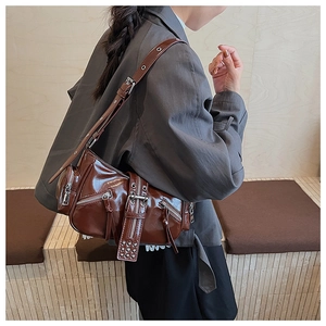 Side view of a vintage dark brown high-gloss motorcycle style shoulder bag on a model