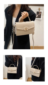 Detail shot of a creamy white lychee grain leather crossbody bag with golden turn-lock