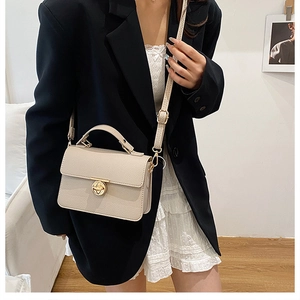 Chic beige textured leather handbag featuring a gold clover twist lock and top handle