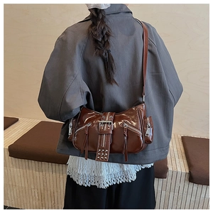 Detailed close-up of dark brown glossy underarm bag with metal zippers and rivets