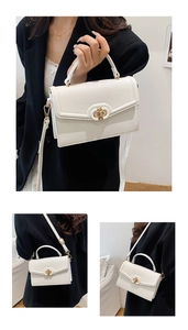 Detail of white litchi pattern handbag with gold twist lock and adjustable shoulder strap