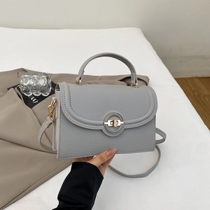 Detail of grey lychee leather texture and golden metal rotary lock on fashion handbag