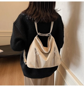 Detail view of the beige versatile backpack featuring vertical zippers and a star charm