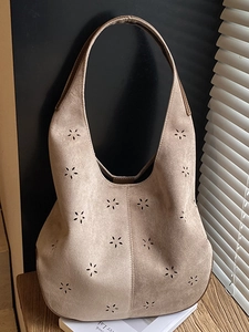 Brown suede hobo bucket bag with laser-cut floral patterns and wide shoulder strap
