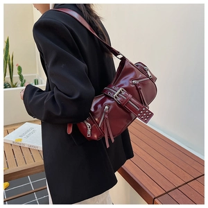 Deep red leather biker bag with silver studs and zippers worn by a model outdoors