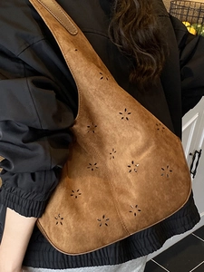 Brown suede hobo bucket bag featuring laser-cut floral patterns and a slouchy design