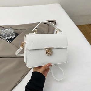 Close-up of white lychee leather square handbag with golden turn-lock and crossbody strap