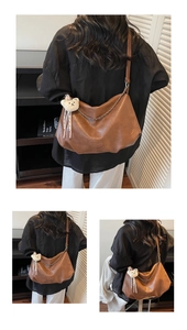Detailed view of brown leather tote bag featuring a decorative metal chain and plush bear charm