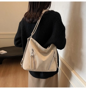 Detail of cream leather tote featuring vertical zippers with silver star charms and tassels