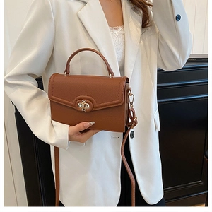 Close-up of brown pebbled texture handbag with a gold bow twist lock and top handle