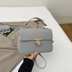 Detailed view of grey pebble leather handbag with gold twist lock and elegant top handle