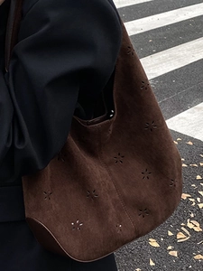 Brown suede bucket bag featuring intricate hollow flower cutouts for autumn fashion