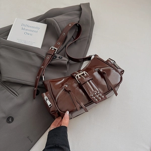 Detailed macro of dark brown biker shoulder bag featuring metallic zippers and buckles