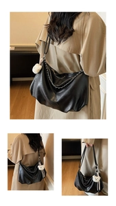 Detail view of black hobo bag with silver chain and cute white bear pendant