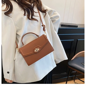 Close-up of brown litchi pattern leather handbag with gold circular twist lock
