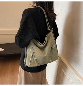 Detail of sage green tote bag with star zippers and embossed text in cozy room