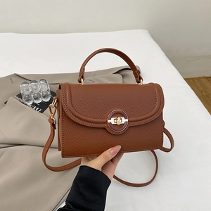 Detail of classic brown leather crossbody bag with a round golden metallic buckle