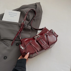 Close-up of wine red vintage motorcycle shoulder bag featuring metal zippers and rivets