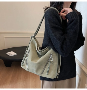 Detail view of sage green tote bag with star zippers and elegant tassel accents