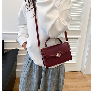 Detail view of burgundy leather crossbody bag with metal turn-lock and adjustable strap
