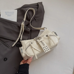 Detail view of cream PU leather shoulder bag with silver studs and zipper pockets on grey blazer