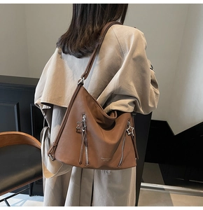 Detailed view of brown leather tote bag featuring unique star zipper and tassel accents