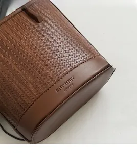 Detail of woven brown shoulder bag showing flat base with SERENDIPITY embossed logo