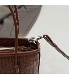 Detailed macro shot of silver metal buckles and woven texture on a brown bucket bag