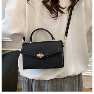 Detailed side view of black pebble leather crossbody bag with elegant gold twist lock hardware