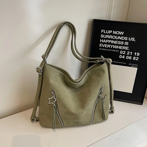 Detail view of sage green faux suede tote bag featuring star charm and leather tassels