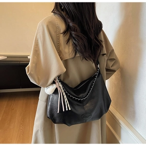 Close-up of black crossbody bag with silver chain and cute bear charm pendant