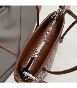 Detail of a brown woven leather tote bag featuring a smooth silver metal zipper closure